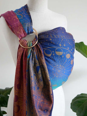 Mannequin wearing a colorful ring sling with celestial patterns on a white background