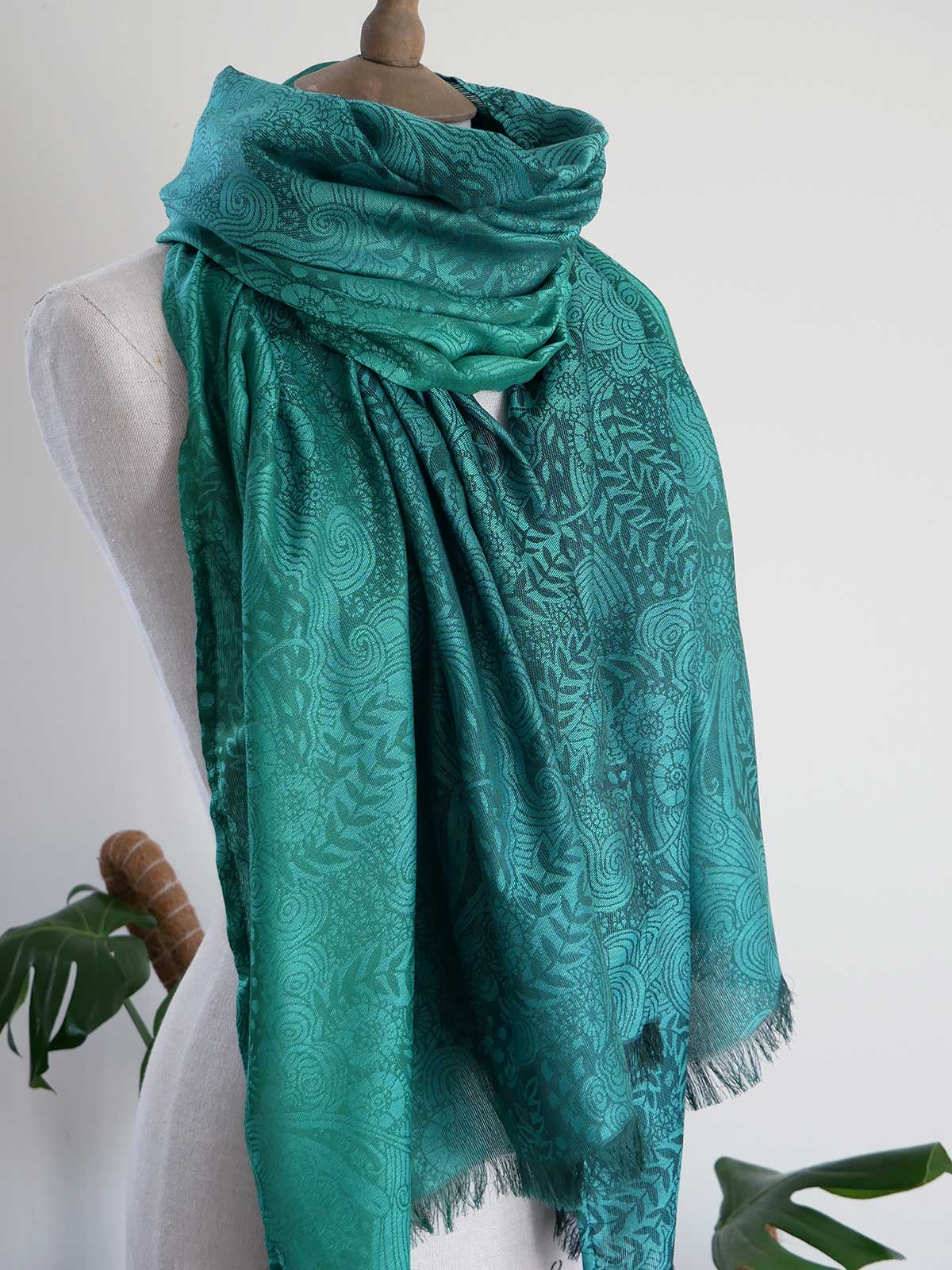 Teal patterned scarf on a mannequin against a white background