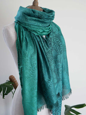 Teal patterned scarf on a mannequin against a white background