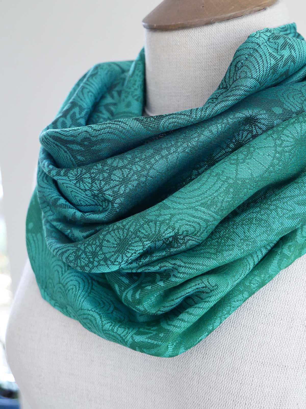 Teal patterned scarf on a mannequin against a white background