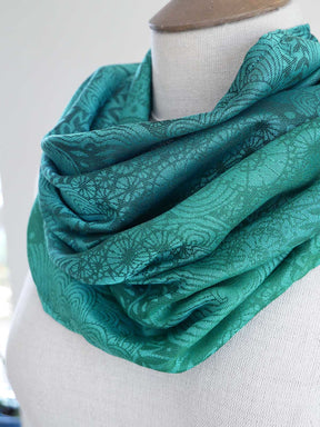 Teal patterned scarf on a mannequin against a white background