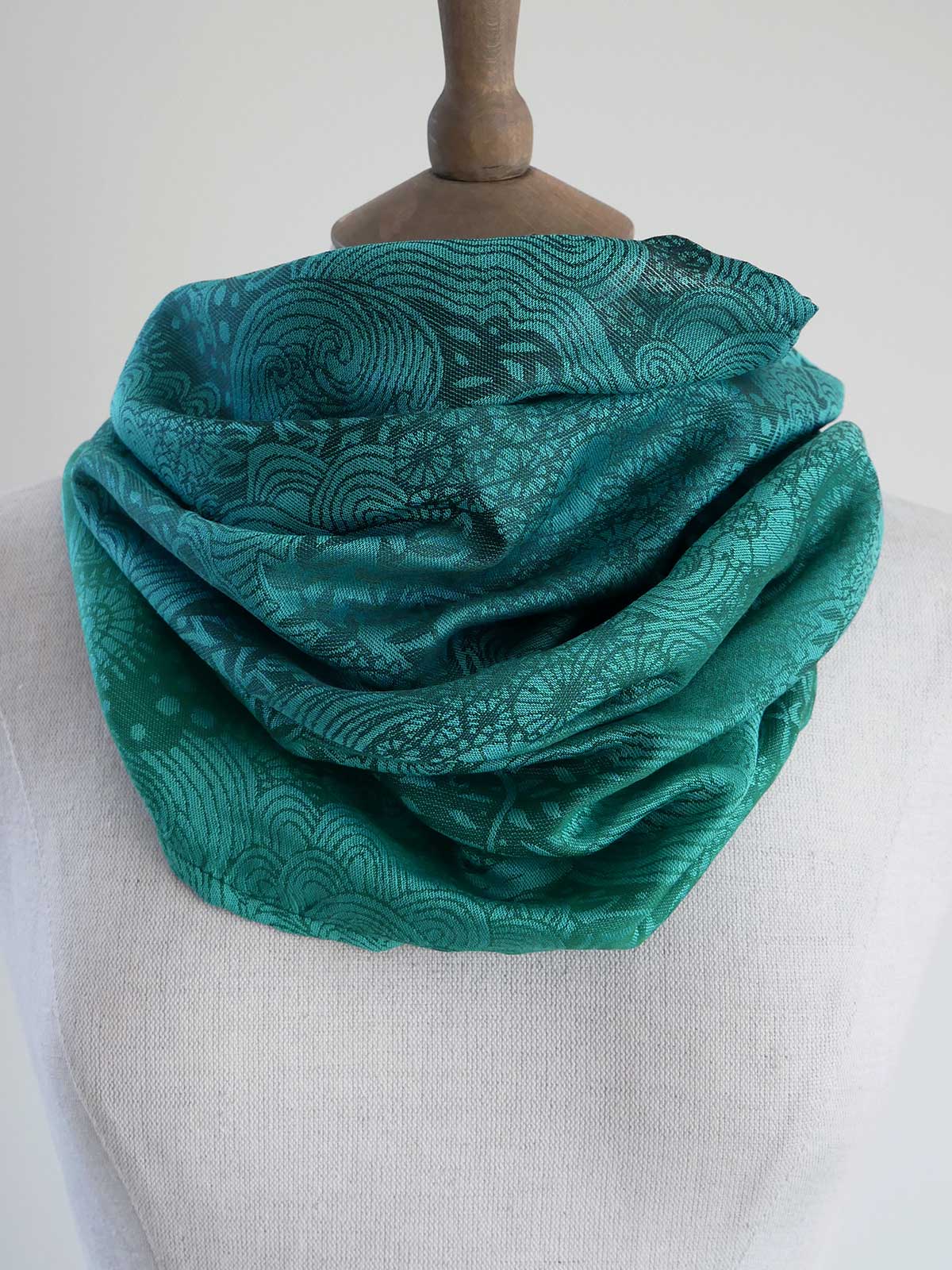 Teal patterned scarf on a mannequin against a white background