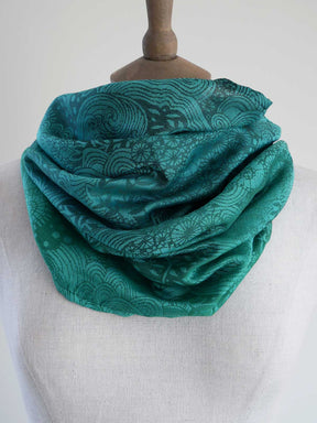 Teal patterned scarf on a mannequin against a white background