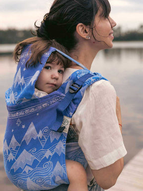Rear view of a child in a blue Onbuhimo with mountain pattern with a hood up.