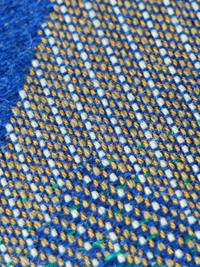 Close-up of a textured fabric with blue, gold, and white pattern