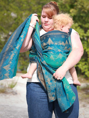 Woman carrying a baby in a blue teal woven wrap with a mountain pattern