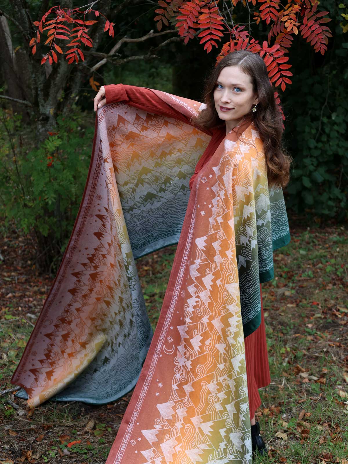 Woman holding a colorful fabric with autumn leaves in the background