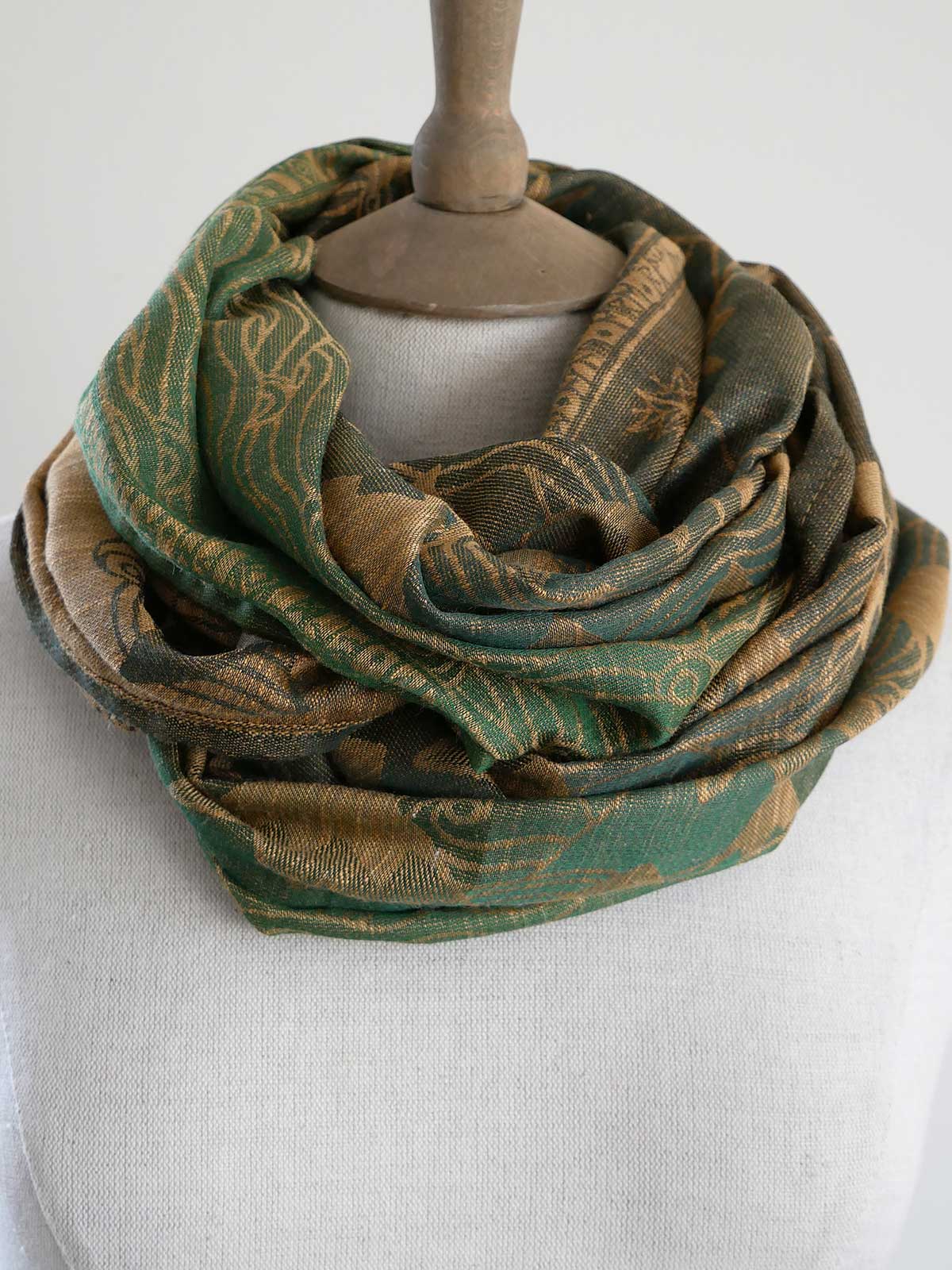 Green and gold patterned scarf on a mannequin against a white background