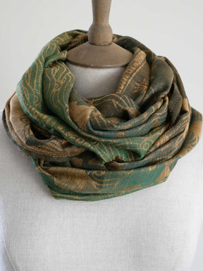 Green and gold patterned scarf on a mannequin against a white background