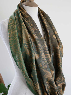 Green and gold patterned scarf on a mannequin against a white background