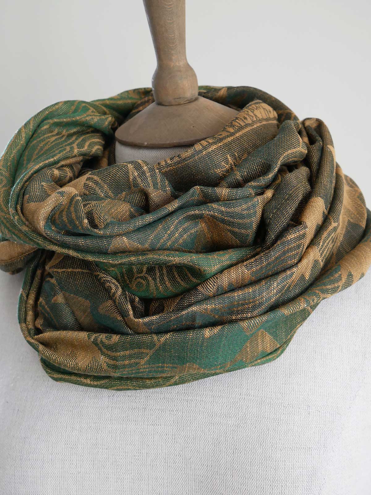 Green and gold loop on a mannequin head against a white background
