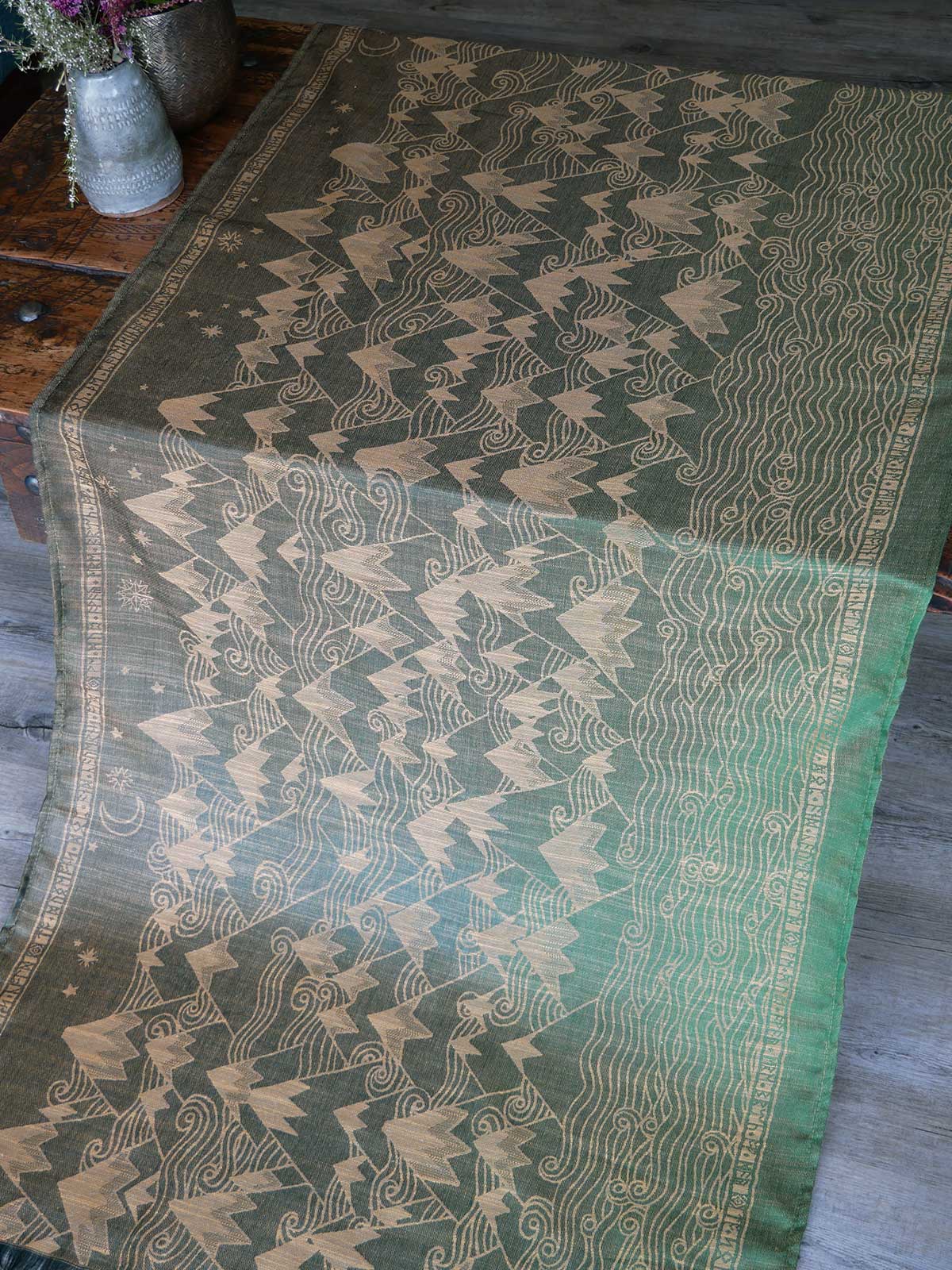 Green and gold patterned fabric on a wooden surface