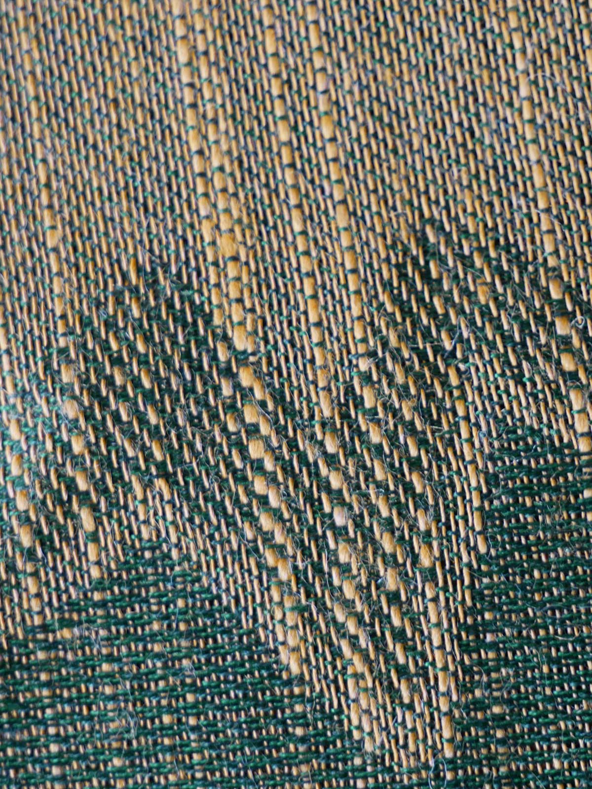 Close-up of a textured fabric with green and gold pattern