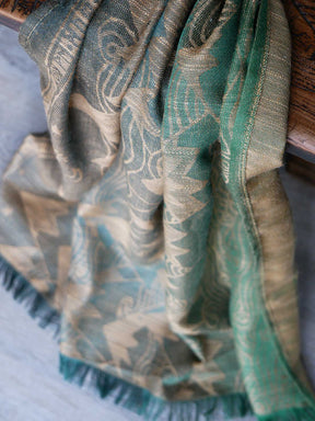 Green and gold patterned fabric draped over a wooden surface