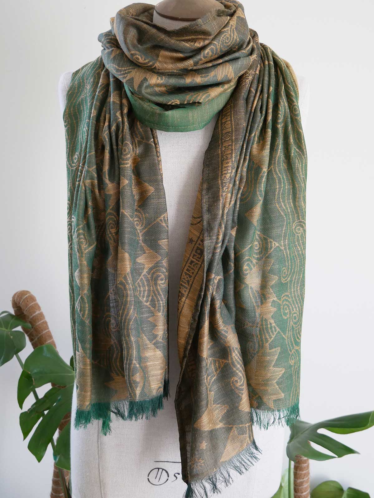 Green patterned scarf on a mannequin with a white background