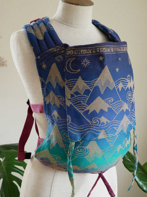 Blue baby carrier with mountain design on a mannequin against a neutral background