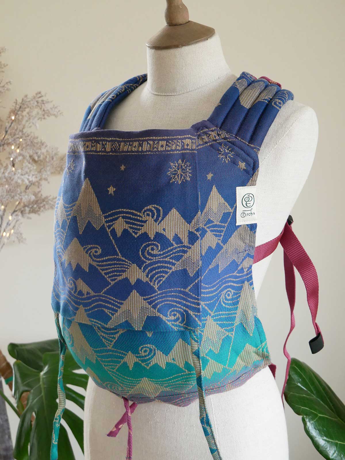 Blue patterned baby carrier on a mannequin with a white background
