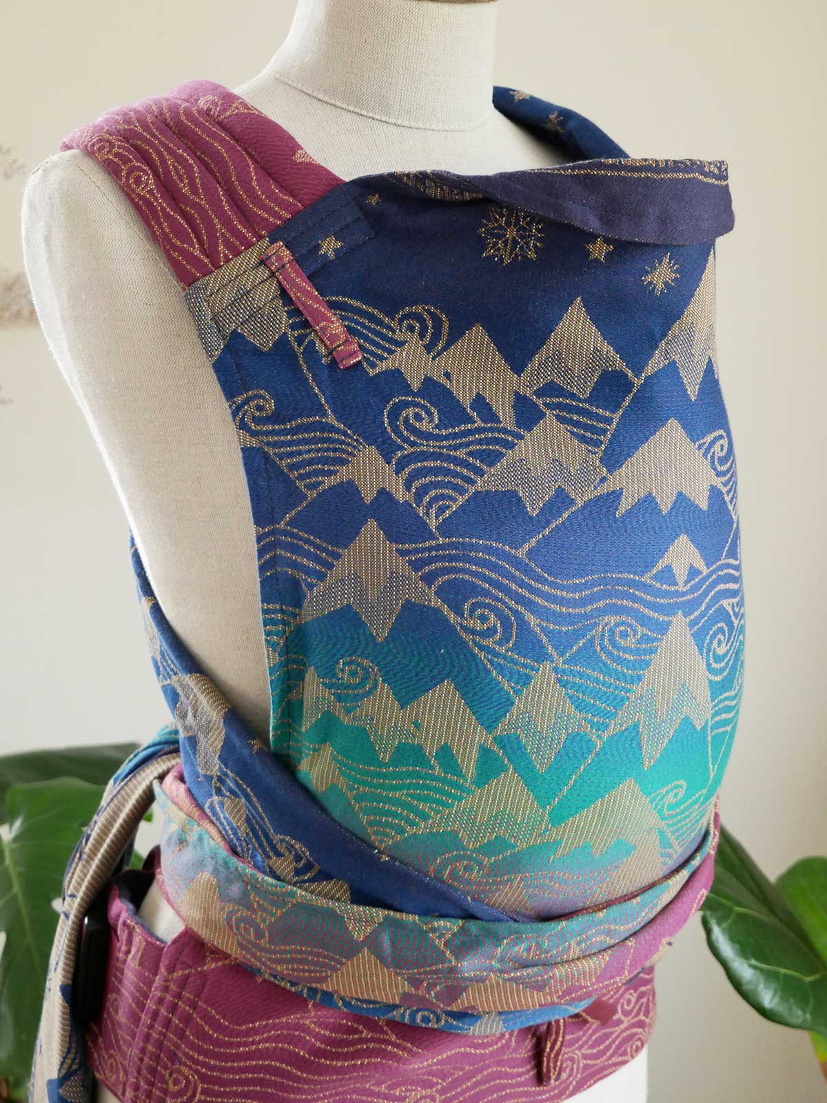 Mannequin wearing a colourful baby carrier with mountain and wave pattern