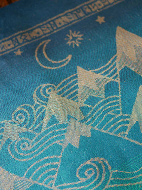 Close up of a blue teal fabric with a gold mountain pattern