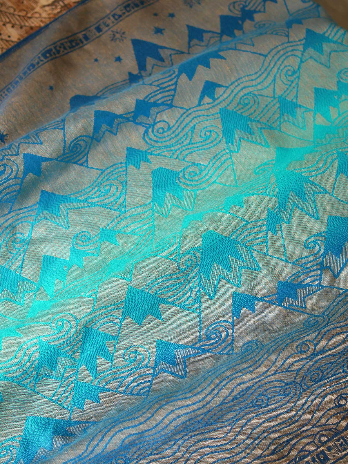 Reverse of a blue teal fabric with a gold mountain pattern
