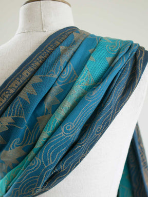 Close up of a blue teal fabric with a gold mountain pattern on a mannequin