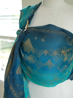 A blue teal ring sling with a gold mountain pattern on a mannequin