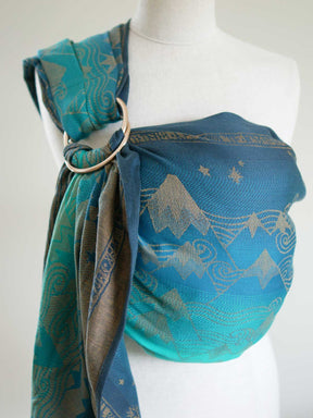 A blue teal ring sling with a gold mountain pattern on a mannequin