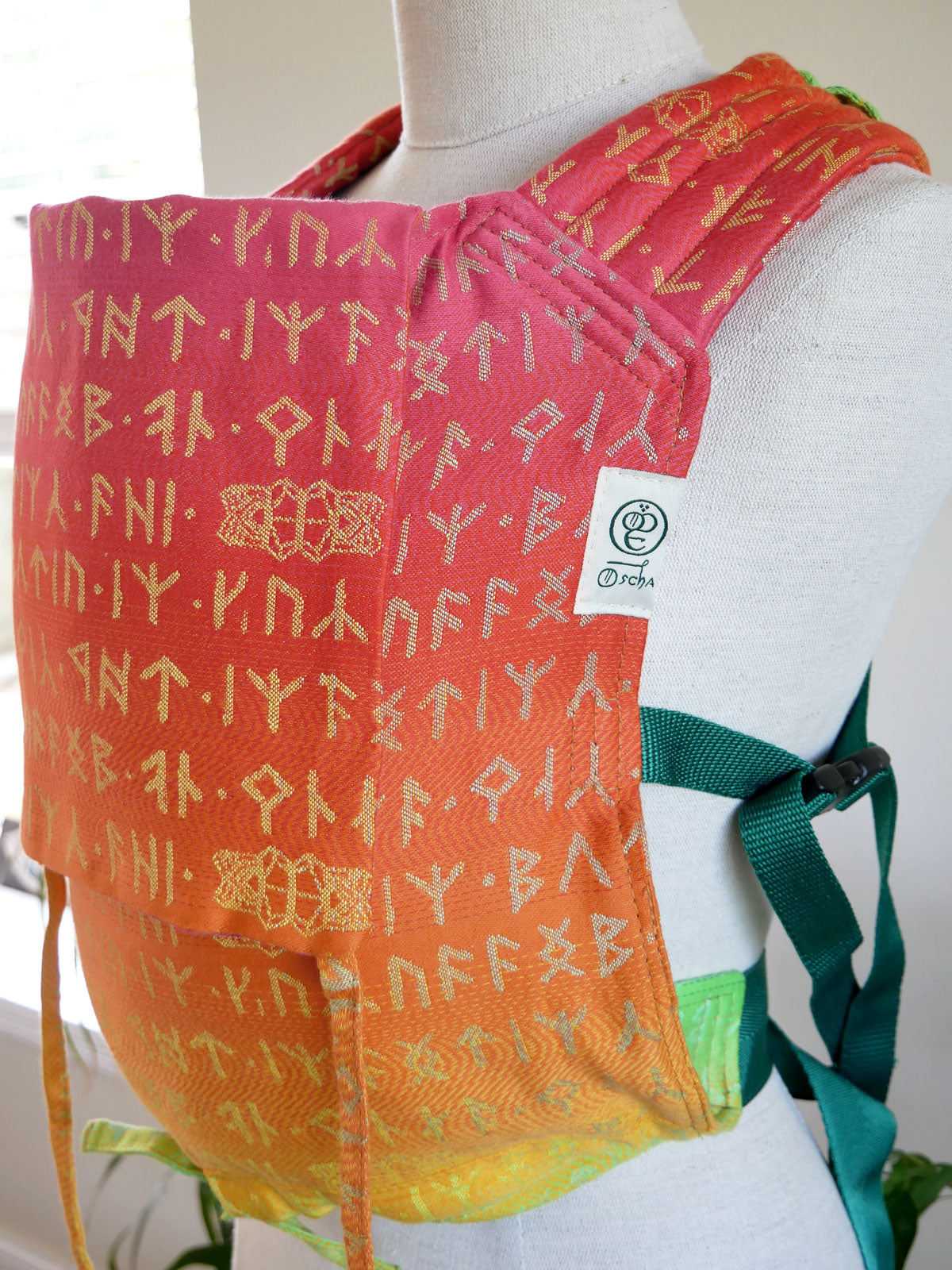 Colorful baby carrier with text pattern on a mannequin against a white background