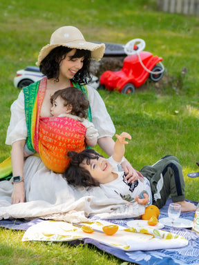 Woman with two children on a blanket in a park setting