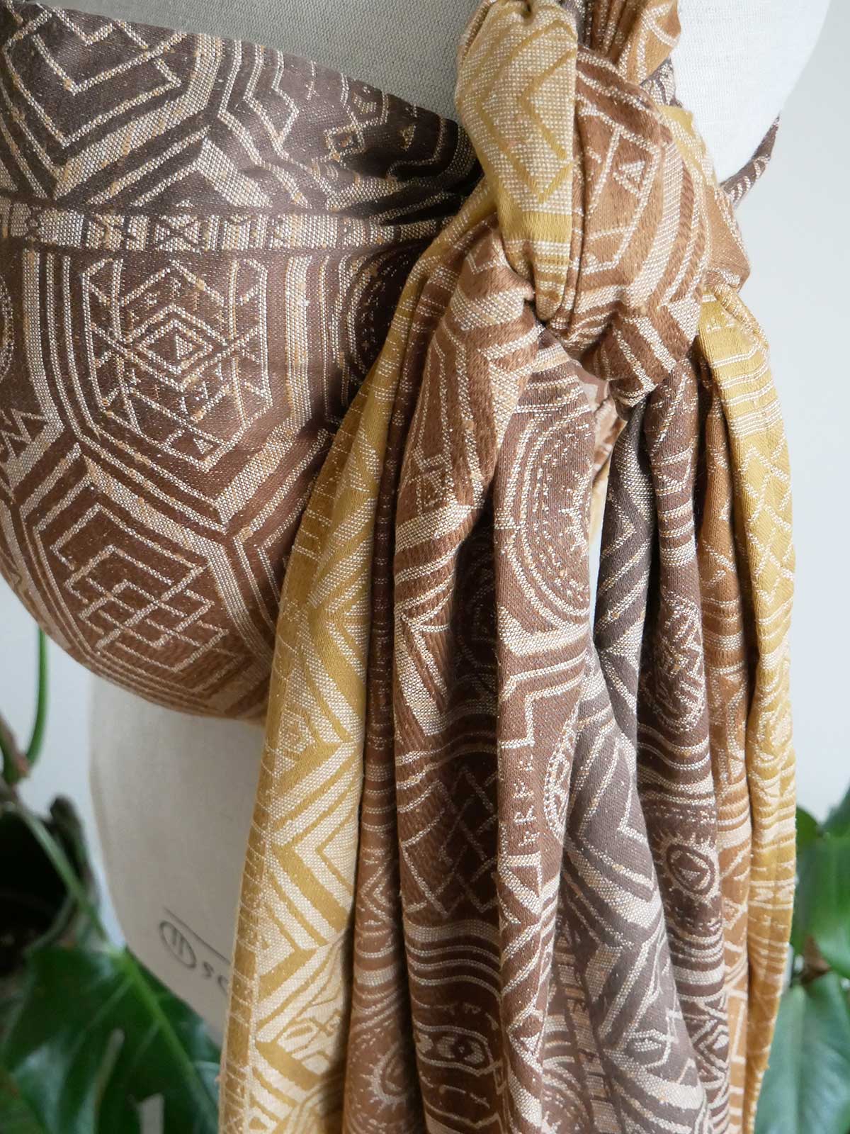 Patterned woven wrap with geometric designs in brown and gold on a white background