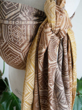 Patterned woven wrap with geometric designs in brown and gold on a white background