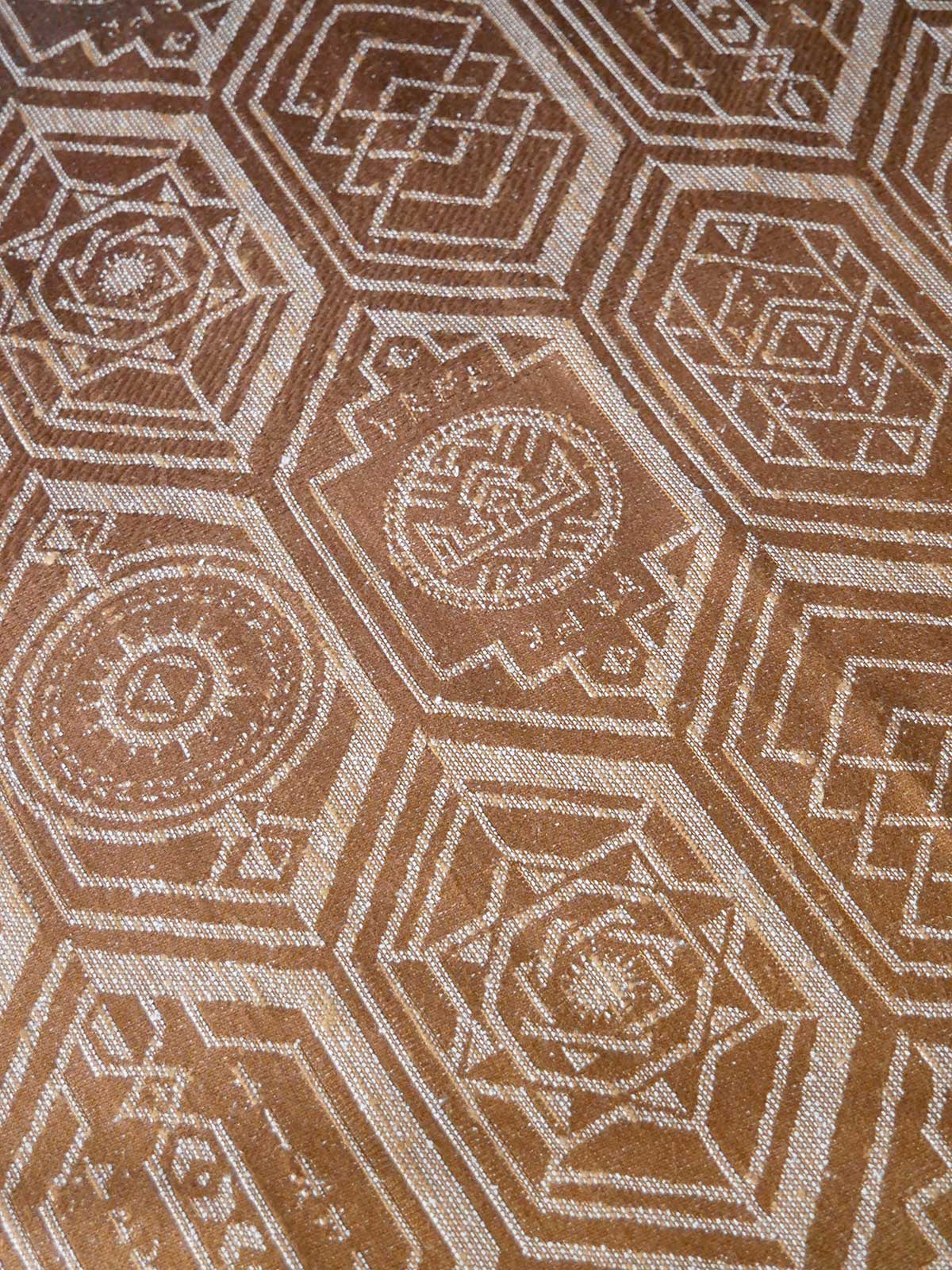 Close-up of a patterned fabric with geometric design in brown and beige.
