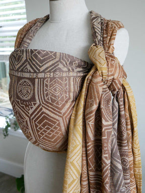 Mannequin wearing Oakenshield Dragon Hoard Baby Wrap with geometric designs in brown and gold.