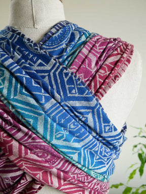 The reverse of a manniquin with a patterned jewel coloured fabric draped.
