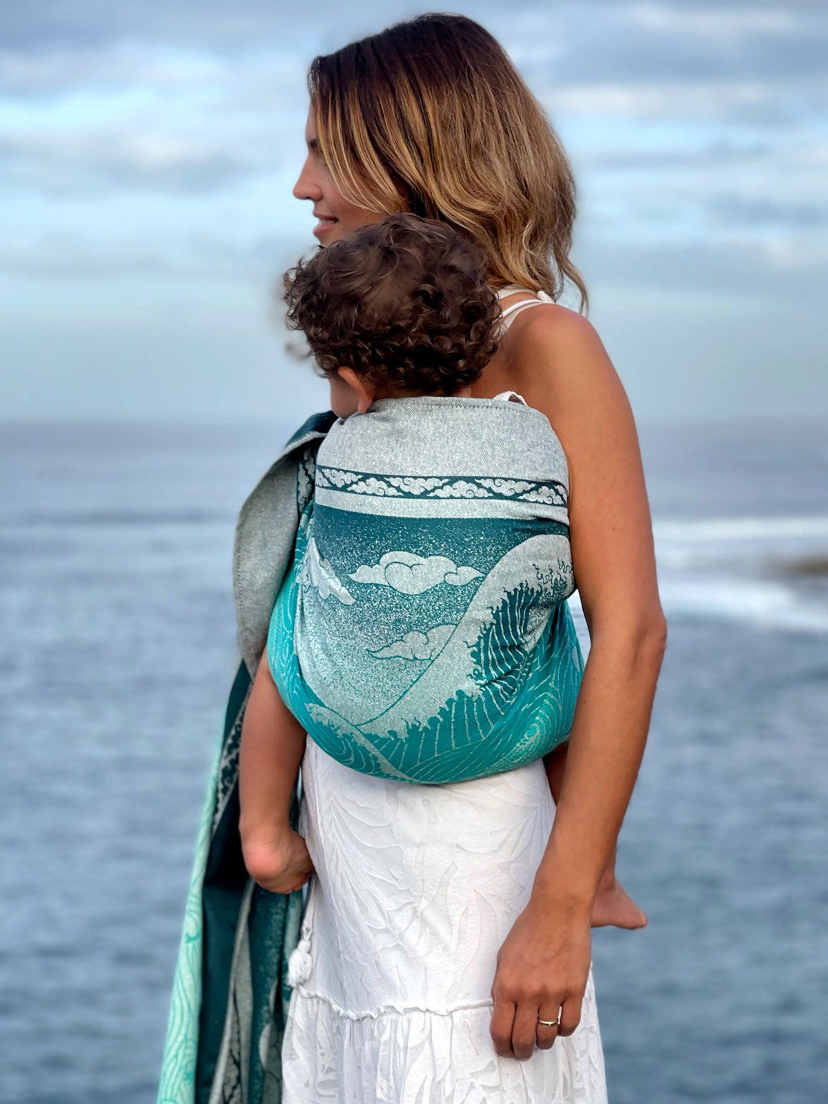 Woman and child on a beach with a teal ring sling.