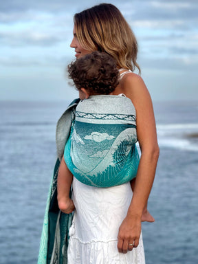 Woman and child on a beach with a teal ring sling.