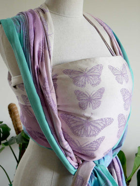Mannequin wearing a baby wrap with butterfly pattern.