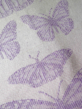 Close-up of fabric with purple butterfly pattern on gray background