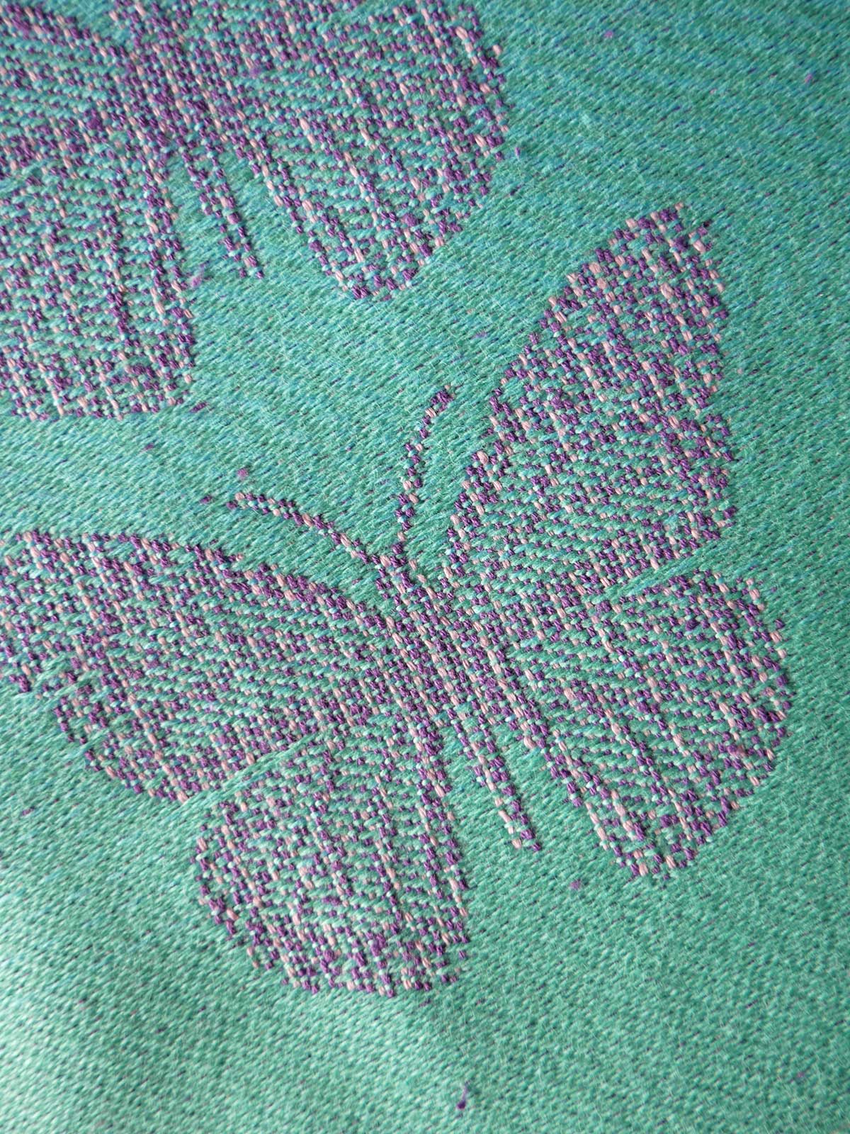 Close-up of a textured green fabric with a butterfly design.