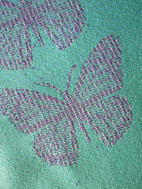 Close-up of a textured green fabric with a butterfly design.
