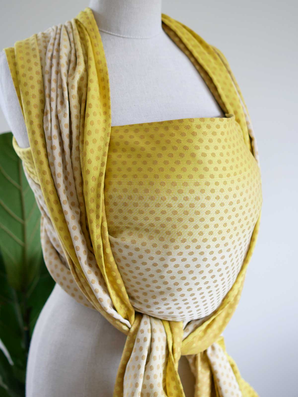 Side view of a lemon and gold woven wrap with dots on a mannequin.