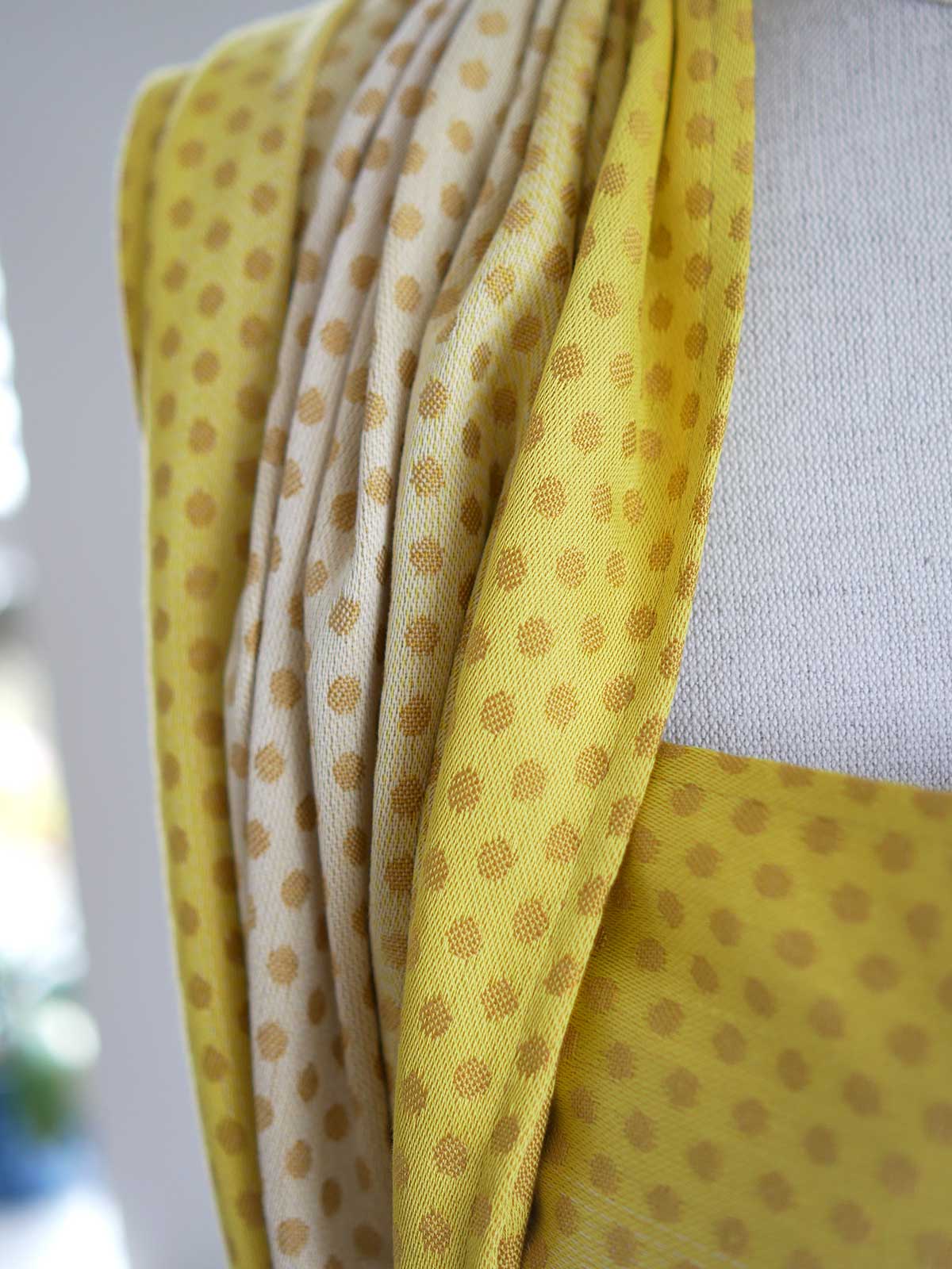 Close up of a lemon and gold woven wrap with dots on a mannequin.