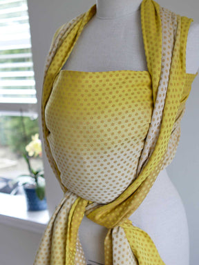 Side view of a lemon and gold woven wrap with dots on a mannequin.