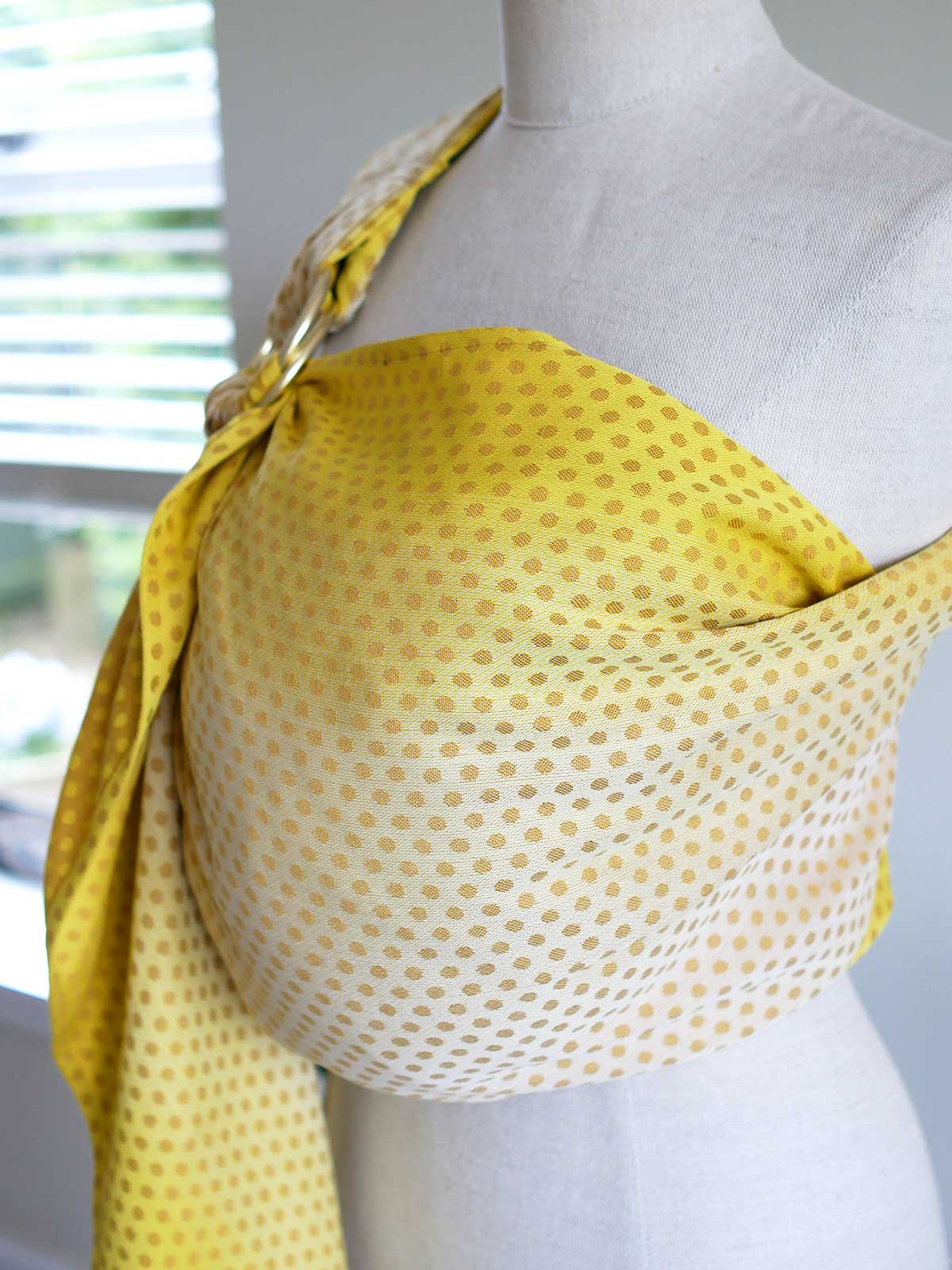Side view of a lemon and gold ring sling with dots on a mannequin.