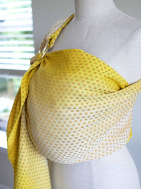 Side view of a lemon and gold ring sling with dots on a mannequin.