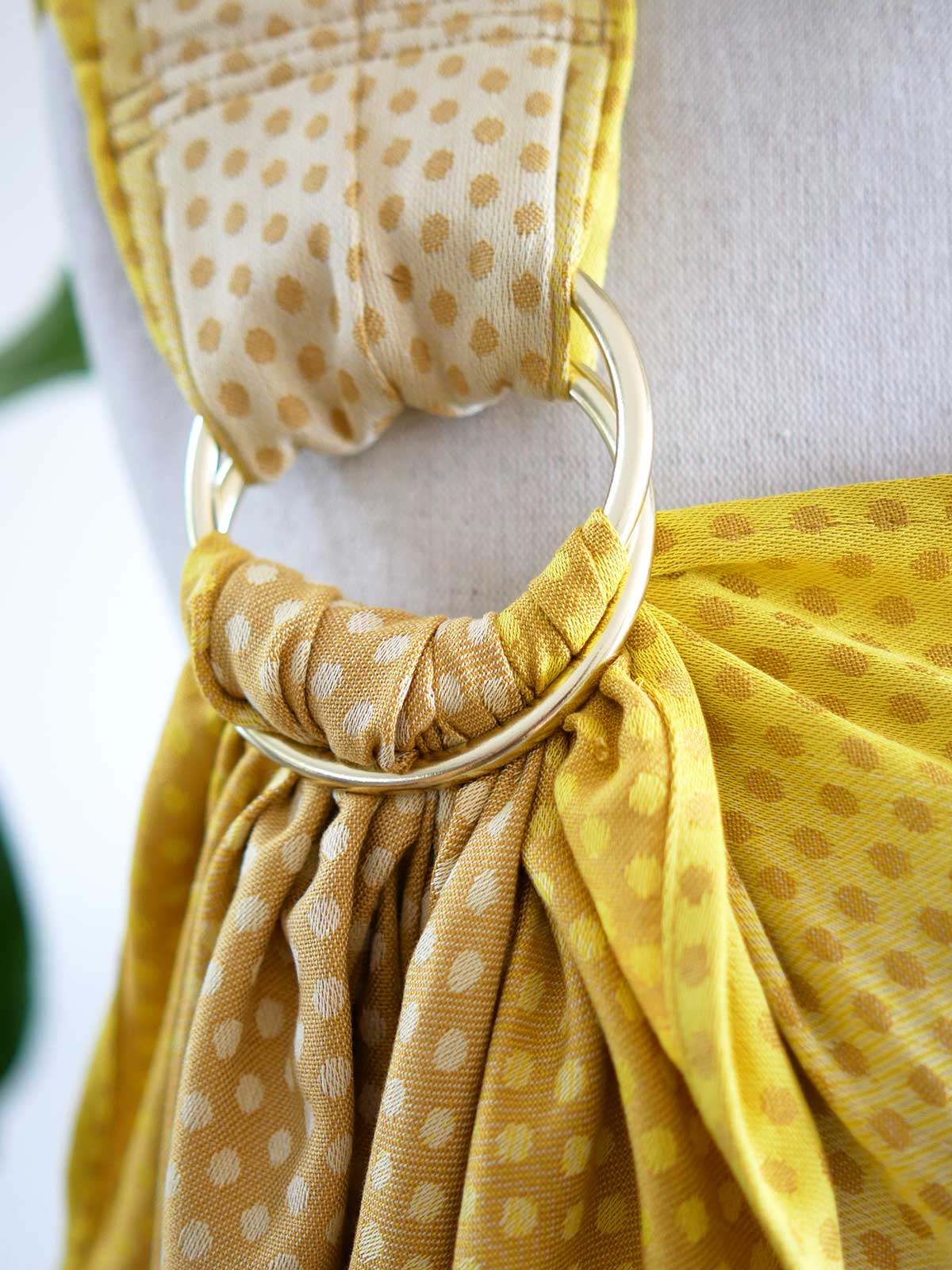 Close up of gold ring on a lemon and gold ring sling with dots on a mannequin.