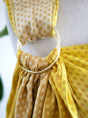 Close up of gold ring on a lemon and gold ring sling with dots on a mannequin.