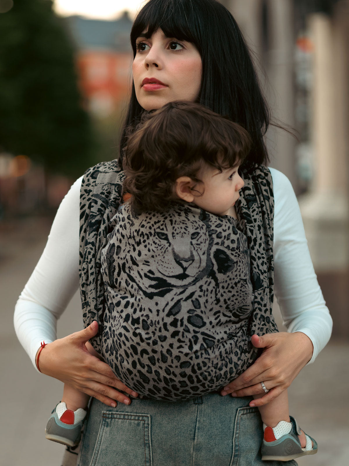 Woman carrying a child in a leopard print Prowl Savannah Baby Wrap.