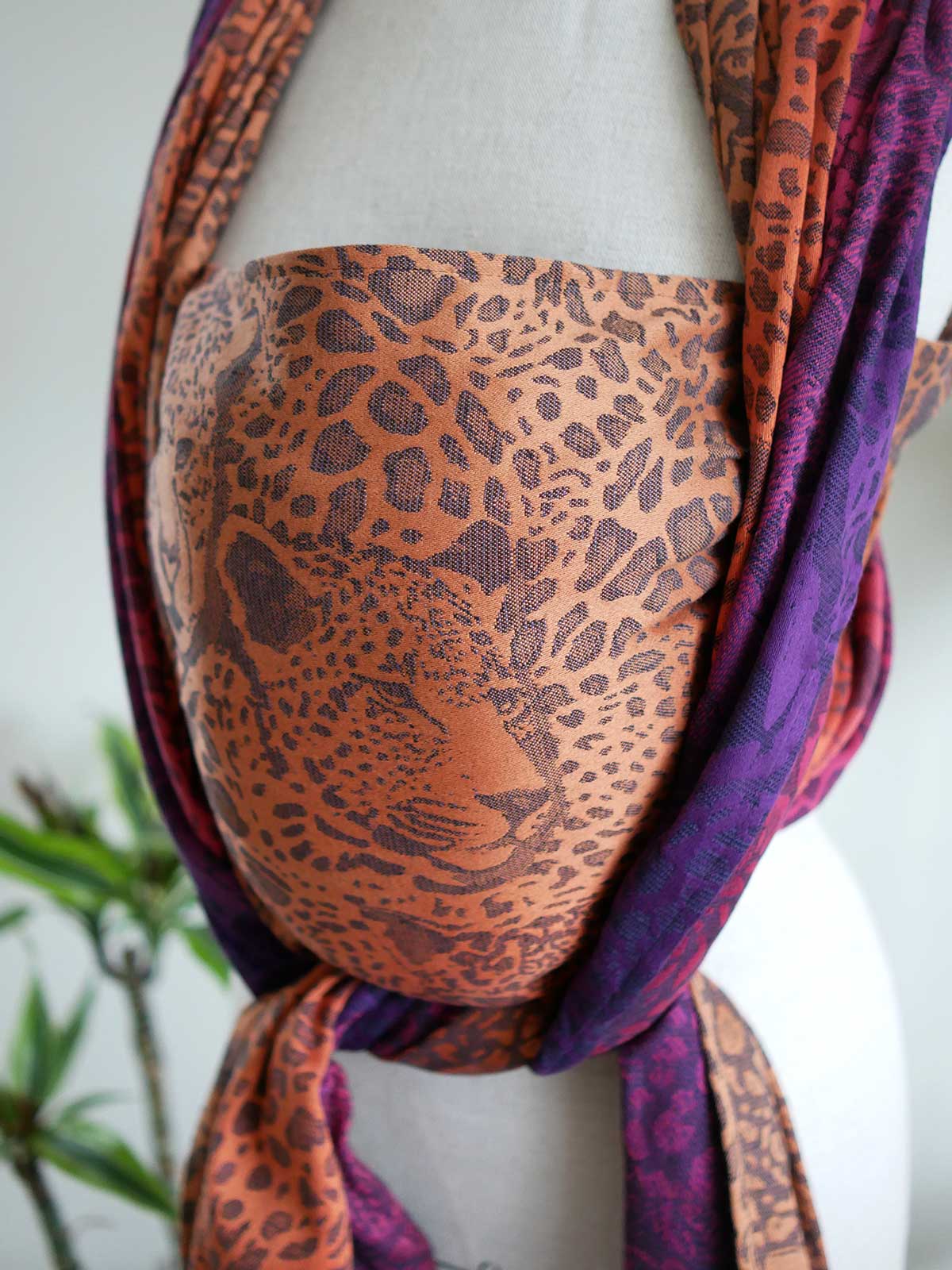 Leopard-print  woven wrap in orange, pink and purple with leopard faces, on a mannequin.