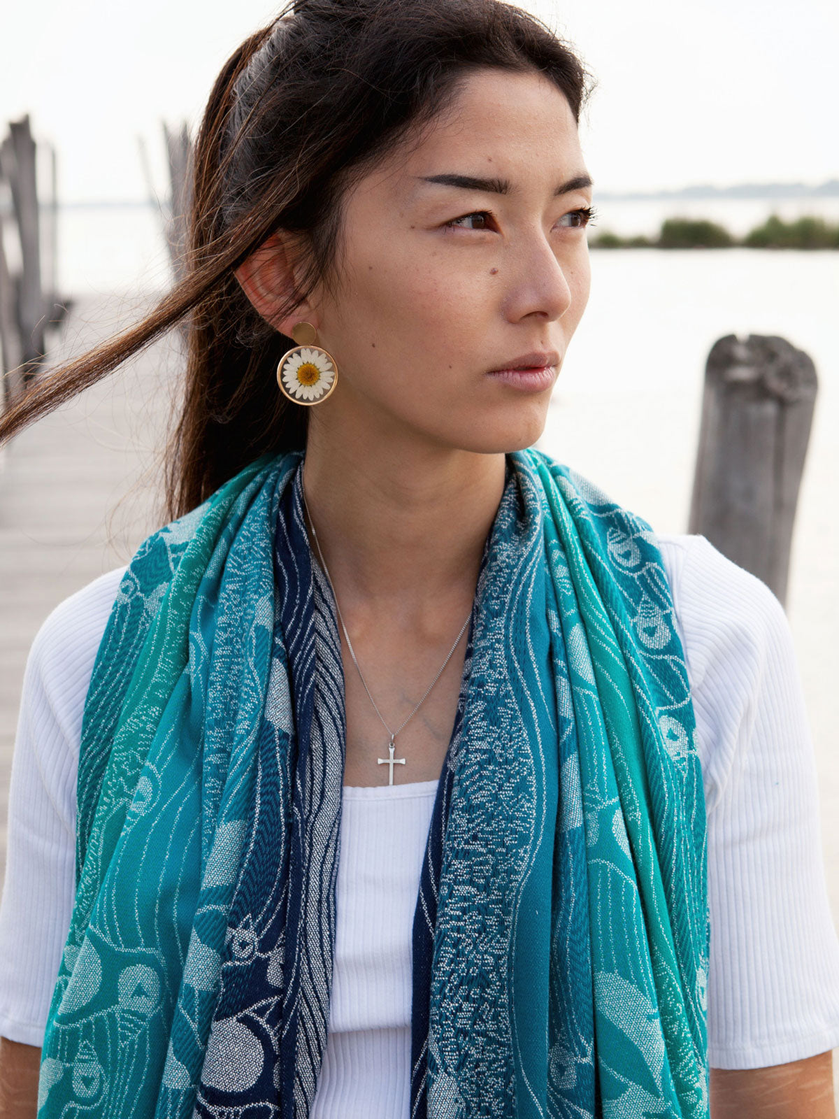 Woman wearing a teal shawl on a pier. 